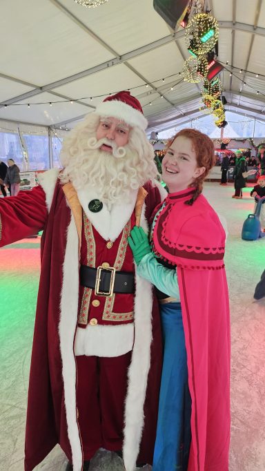 Kerstman met lange baard, poseert met vrouw in roze cape, winterfeest.